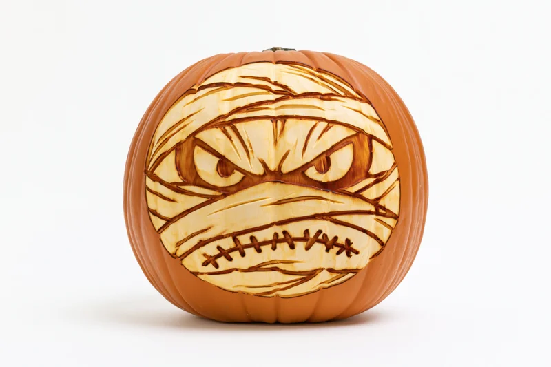 Carved pumpkin with mummy face design on white background