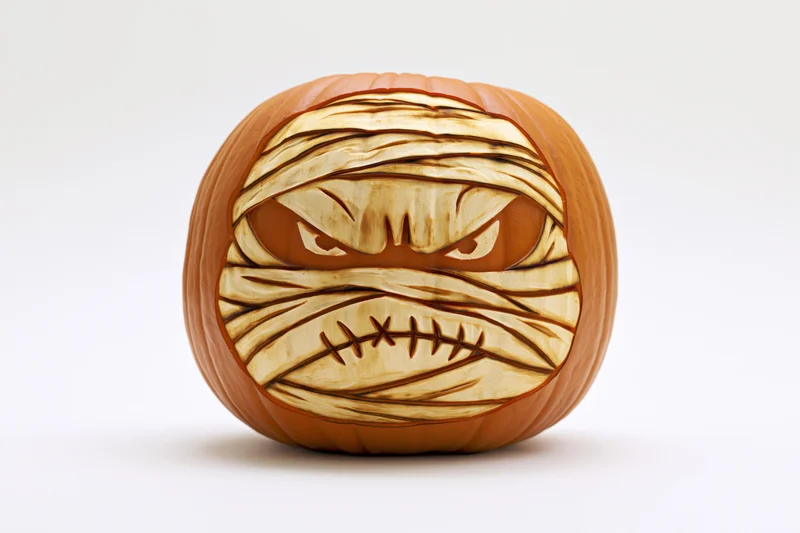 Carved pumpkin with mummy face design on white background