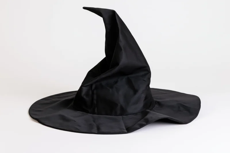 Black fabric witch hat with floppy pointed crown on white background