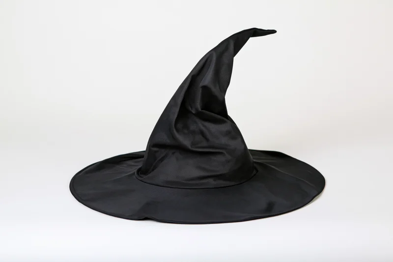 Black witch hat with crooked pointed crown and wide brim on white background