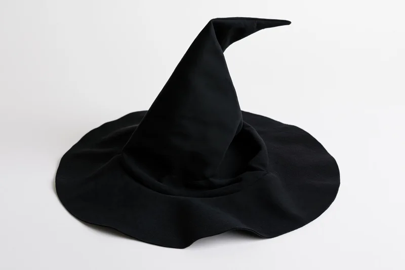 Black fabric witch hat with tall pointed crown and wide brim on white background