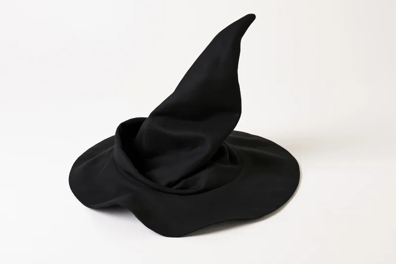 Black fabric witch hat with tall pointed crown and wide brim on white background