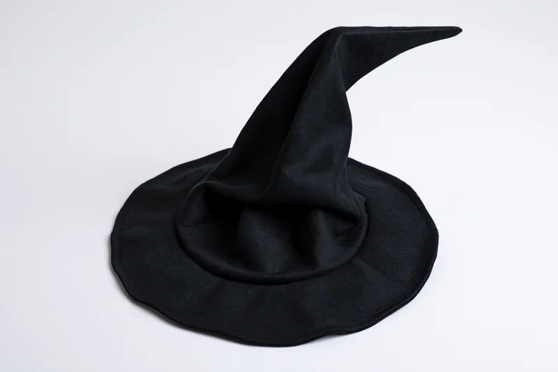 Black witch hat with tall pointed crown and wide brim on white background