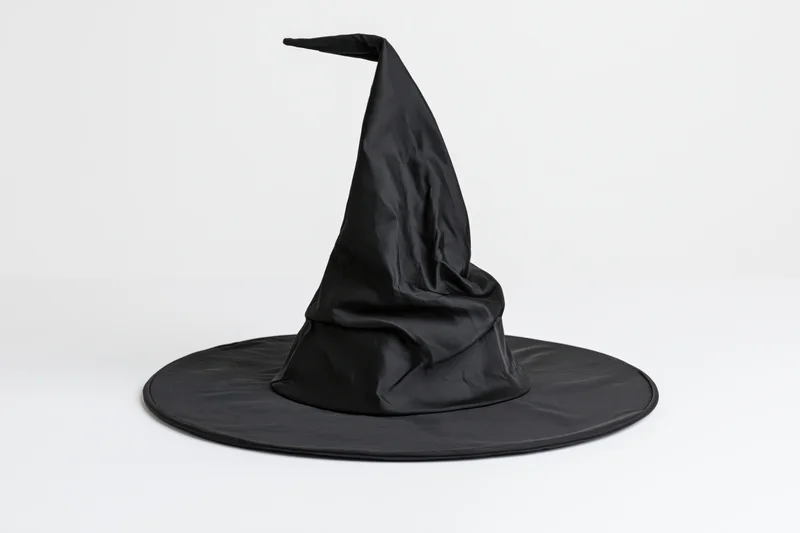 Black pointed witch hat with crumpled fabric on white background