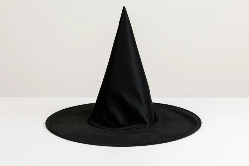 Black pointed witch hat standing upright on a white surface