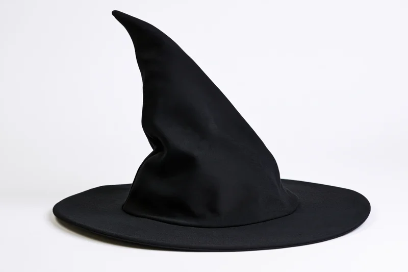 Black witch hat with tall crooked pointed crown and wide brim on white background