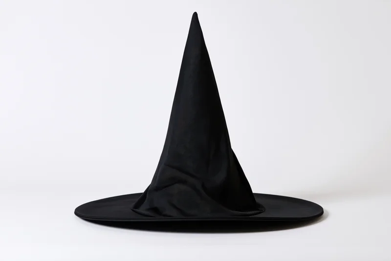 Black witch hat with tall pointed cone and wide flat brim on white background