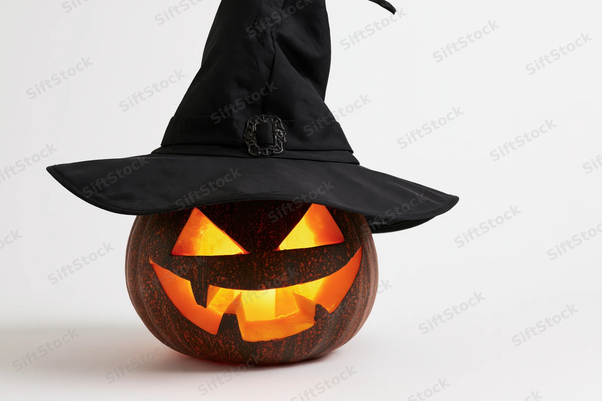 Carved jack-o-lantern with glowing face wearing a tall black witch hat on white background
