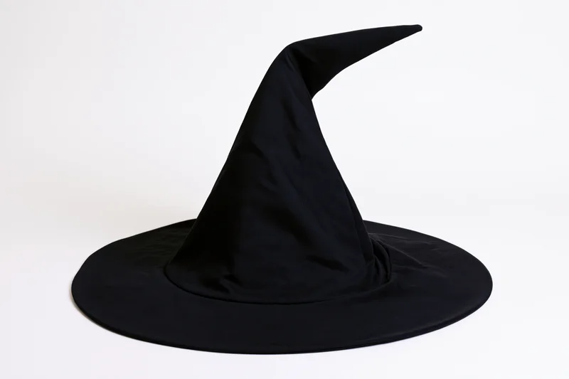 Black witch hat with tall curved pointed crown and wide brim on white background