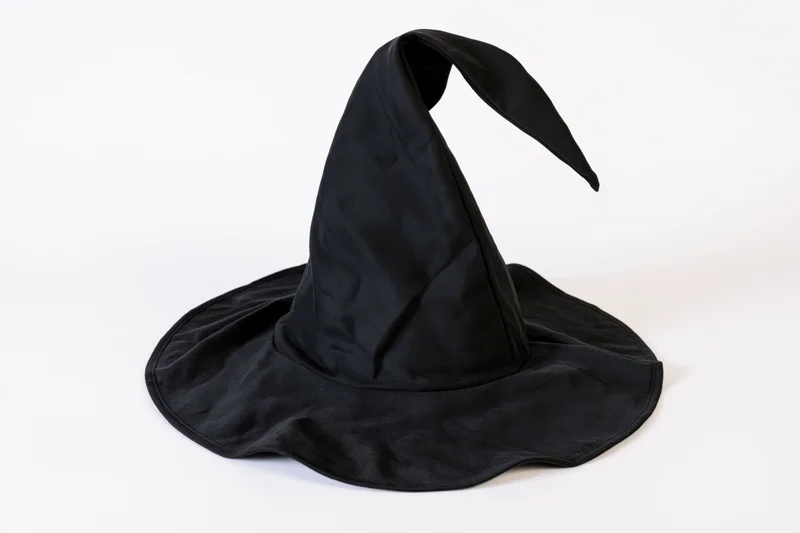Black witch hat with tall curved pointed crown and wide brim on white background