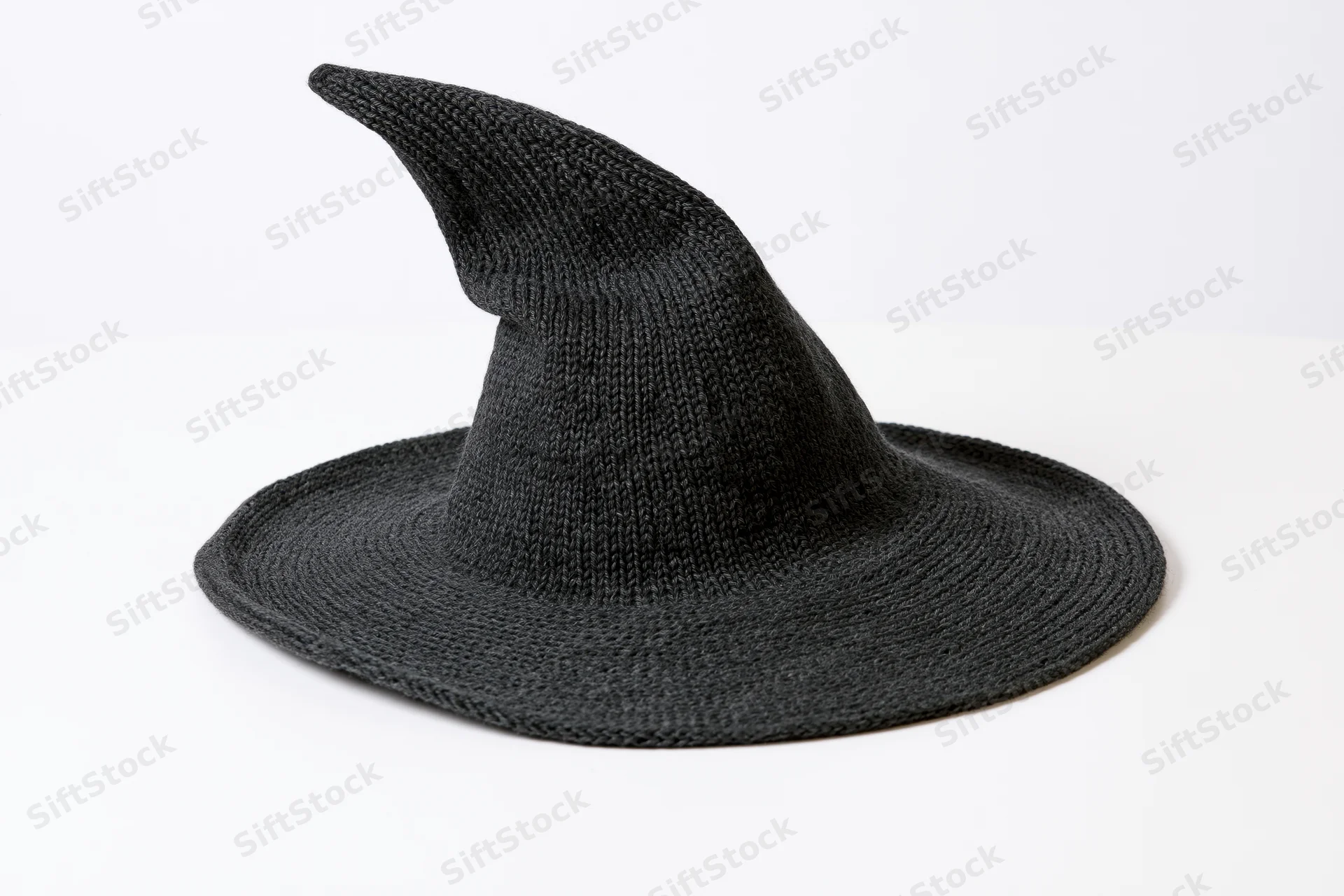 Dark charcoal knitted witch hat with wide brim and pointed top on white surface
