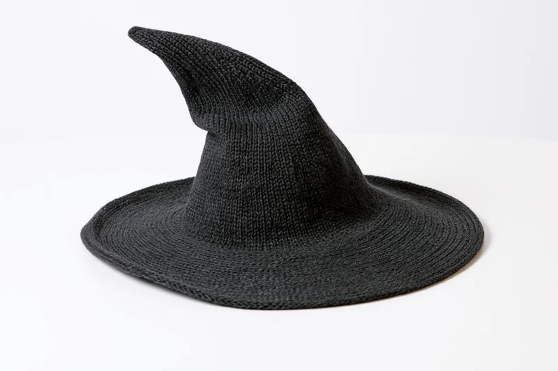 Dark charcoal knitted witch hat with wide brim and pointed top on white surface