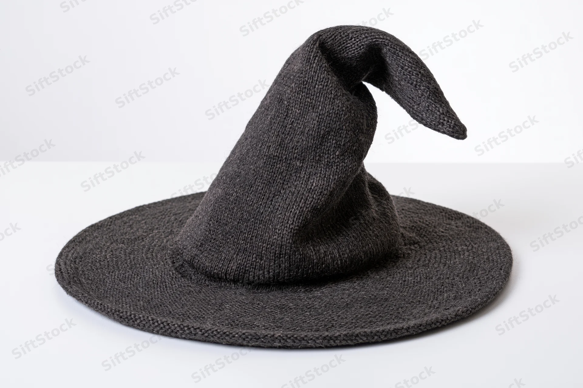 Dark charcoal knitted witch hat with wide brim and pointed tip on white surface