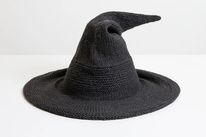 Dark charcoal knitted witch hat with wide brim and pointed tip on white background