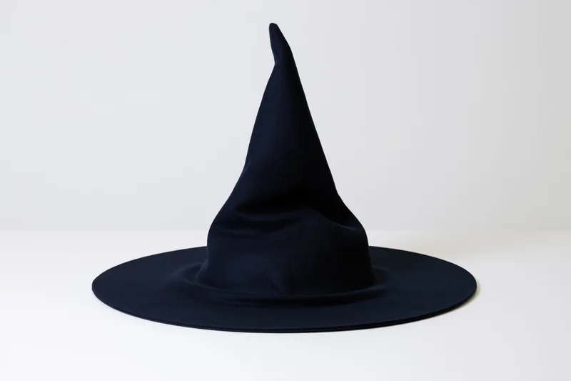 Dark navy witch hat with tall crooked point and wide brim on white surface
