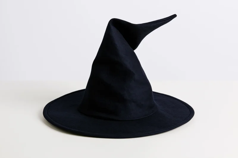 Dark navy witch hat with tall crooked pointed crown on white surface