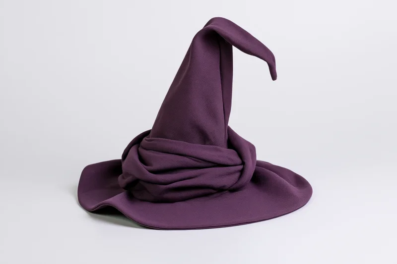 Deep purple fabric witch hat with tall curling tip isolated on white background