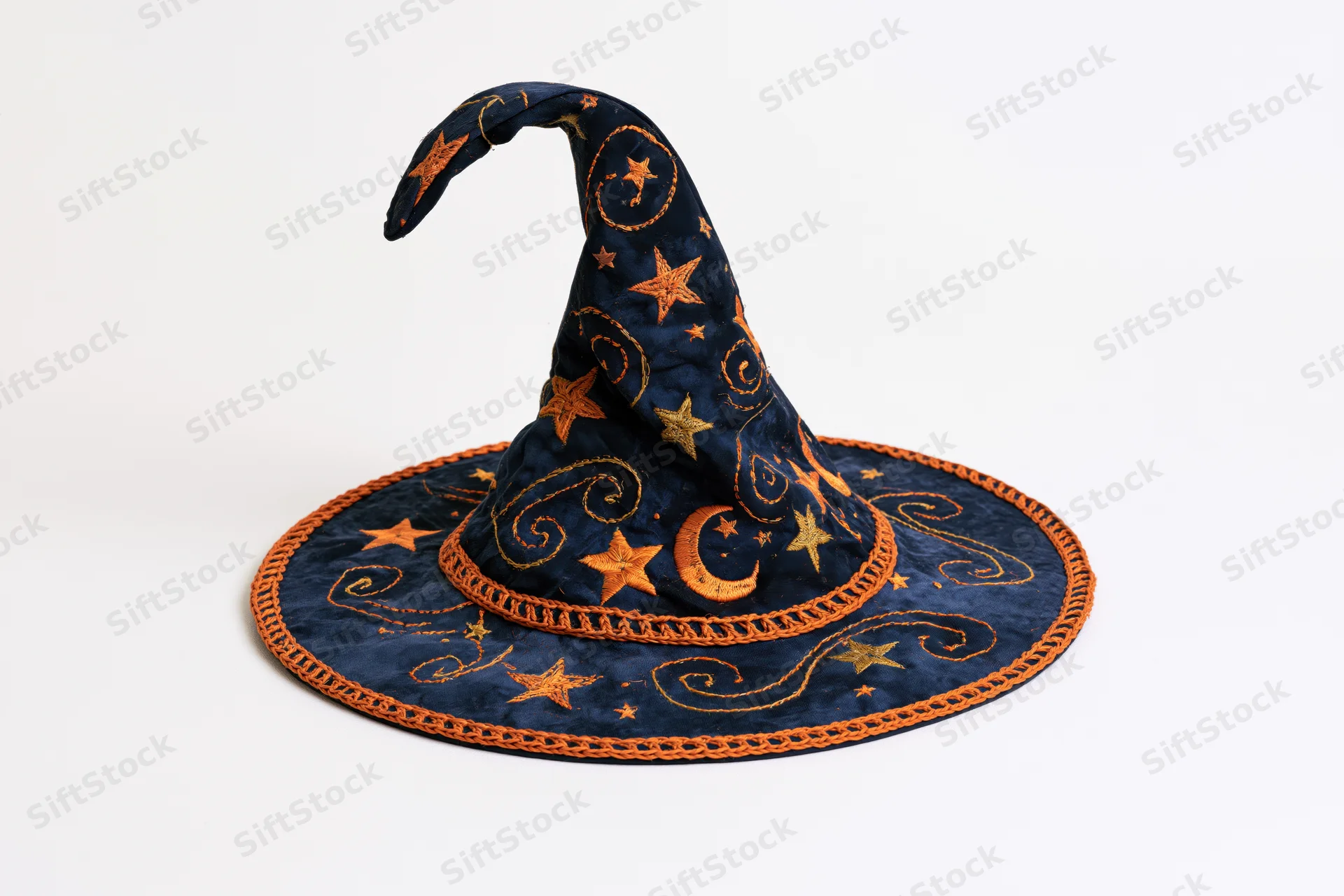Handmade fabric witch hat with embroidered stars and moon, curved tip, navy and orange, lying on white background