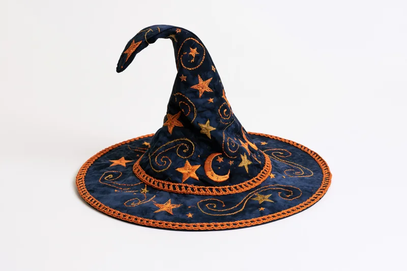 Handmade fabric witch hat with embroidered stars and moon, curved tip, navy and orange, lying on white background