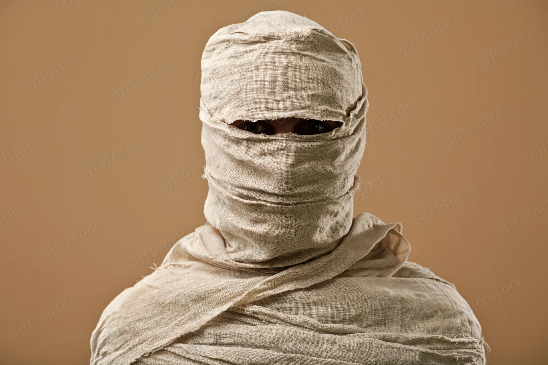 Person wrapped in linen bandages from head to shoulders in studio portrait