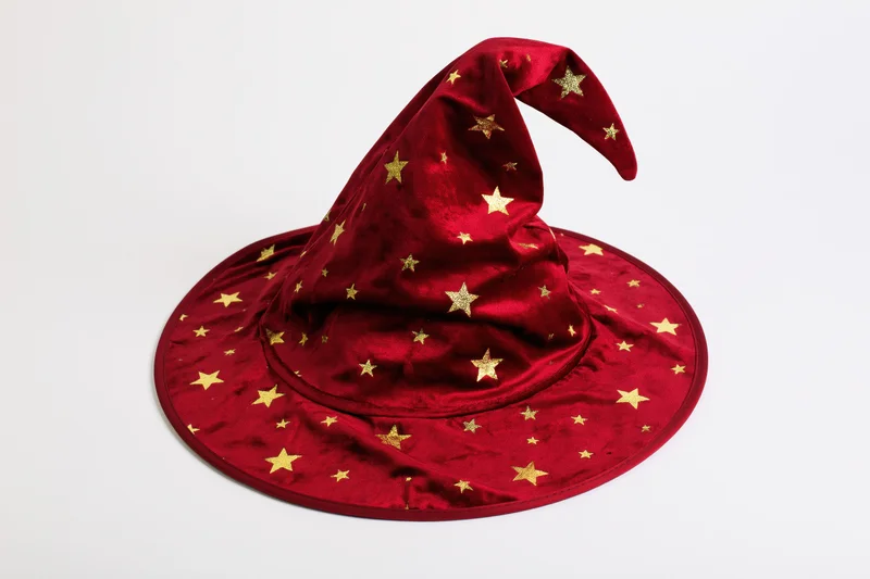 Red velvet witch hat with gold stars and curved tip on white background