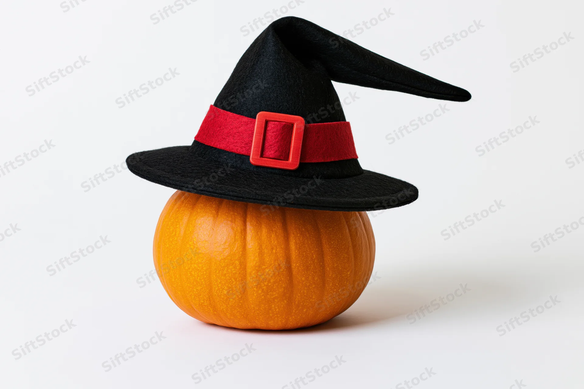 Small orange pumpkin wearing black witch hat on white background
