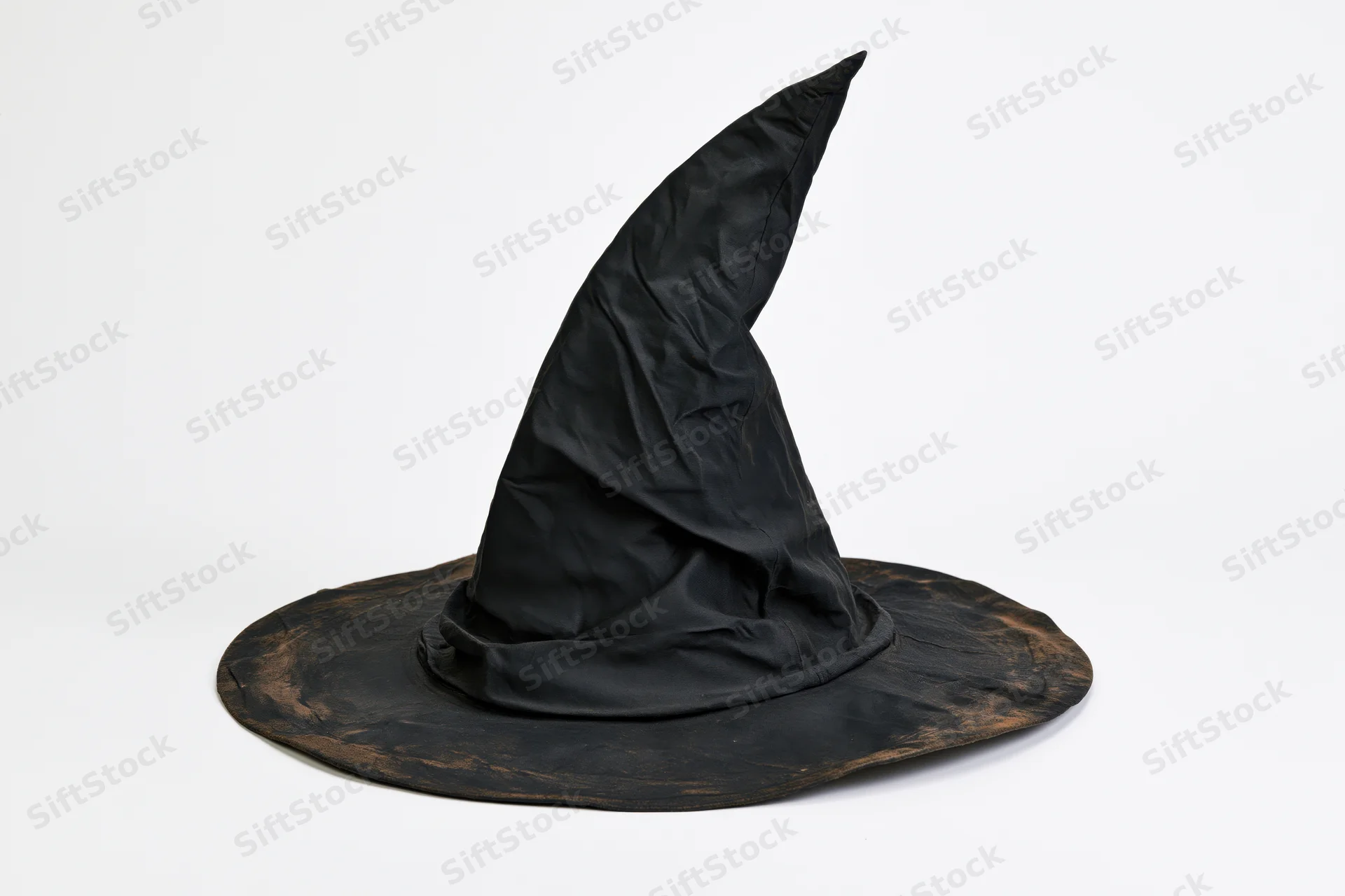 Worn black pointed witch hat resting on white surface