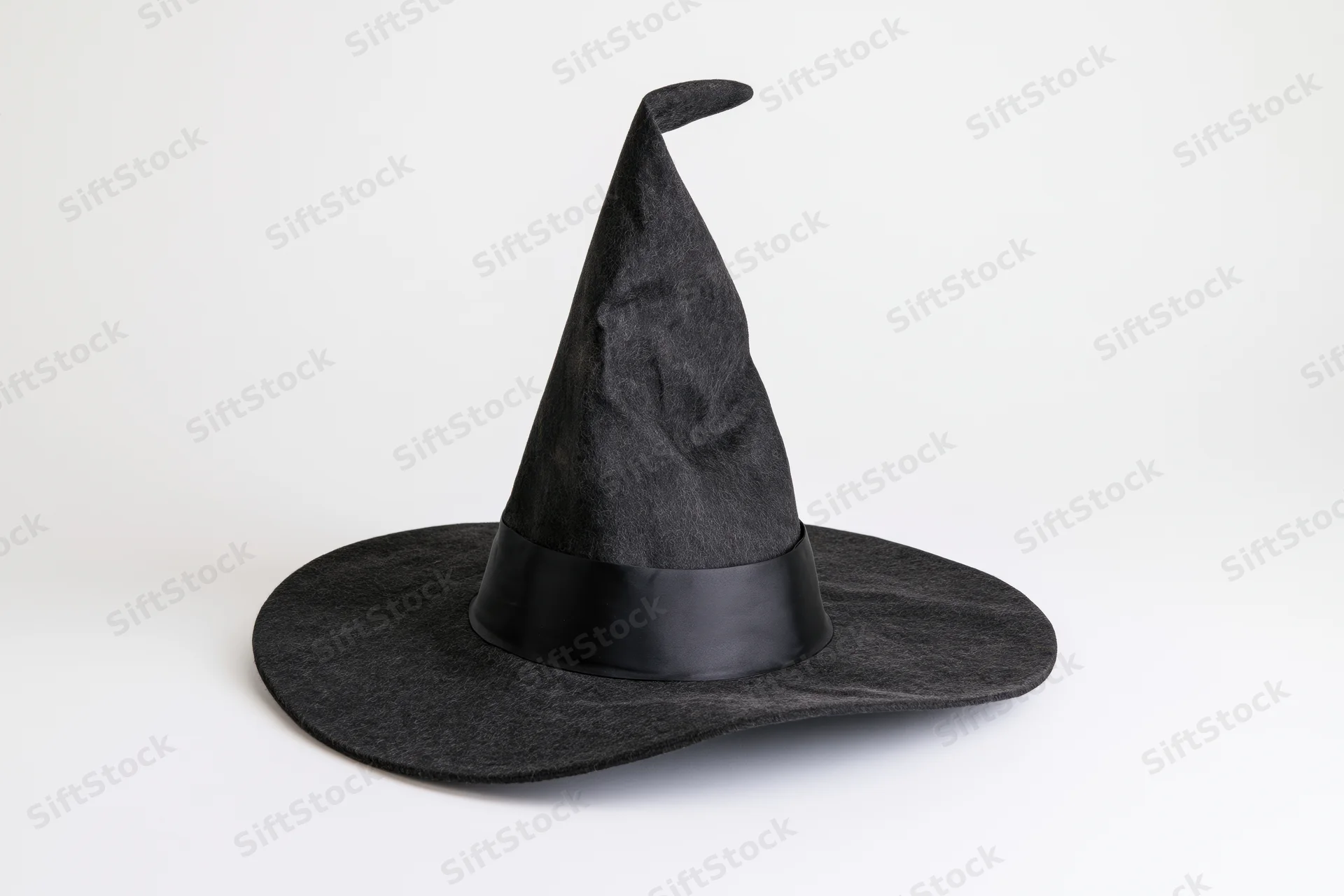 Black pointed witch hat with tilted brim and ribbon band on white background