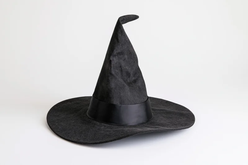 Black pointed witch hat with tilted brim and ribbon band on white background