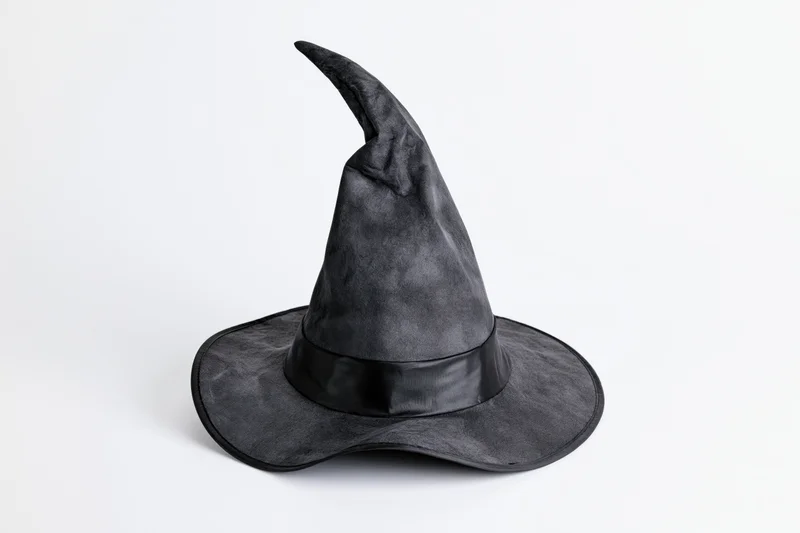 Black pointed witch hat tilted and worn, isolated on white background