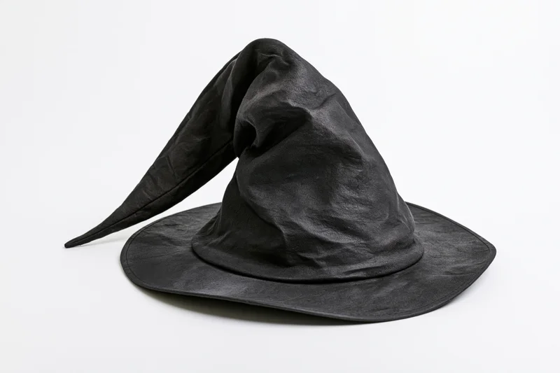 Worn black witch hat with bent drooping tip on white background