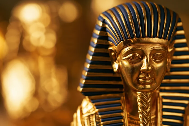 Golden funerary mask of an ancient egyptian pharaoh with blue striped headdress and ceremonial beard