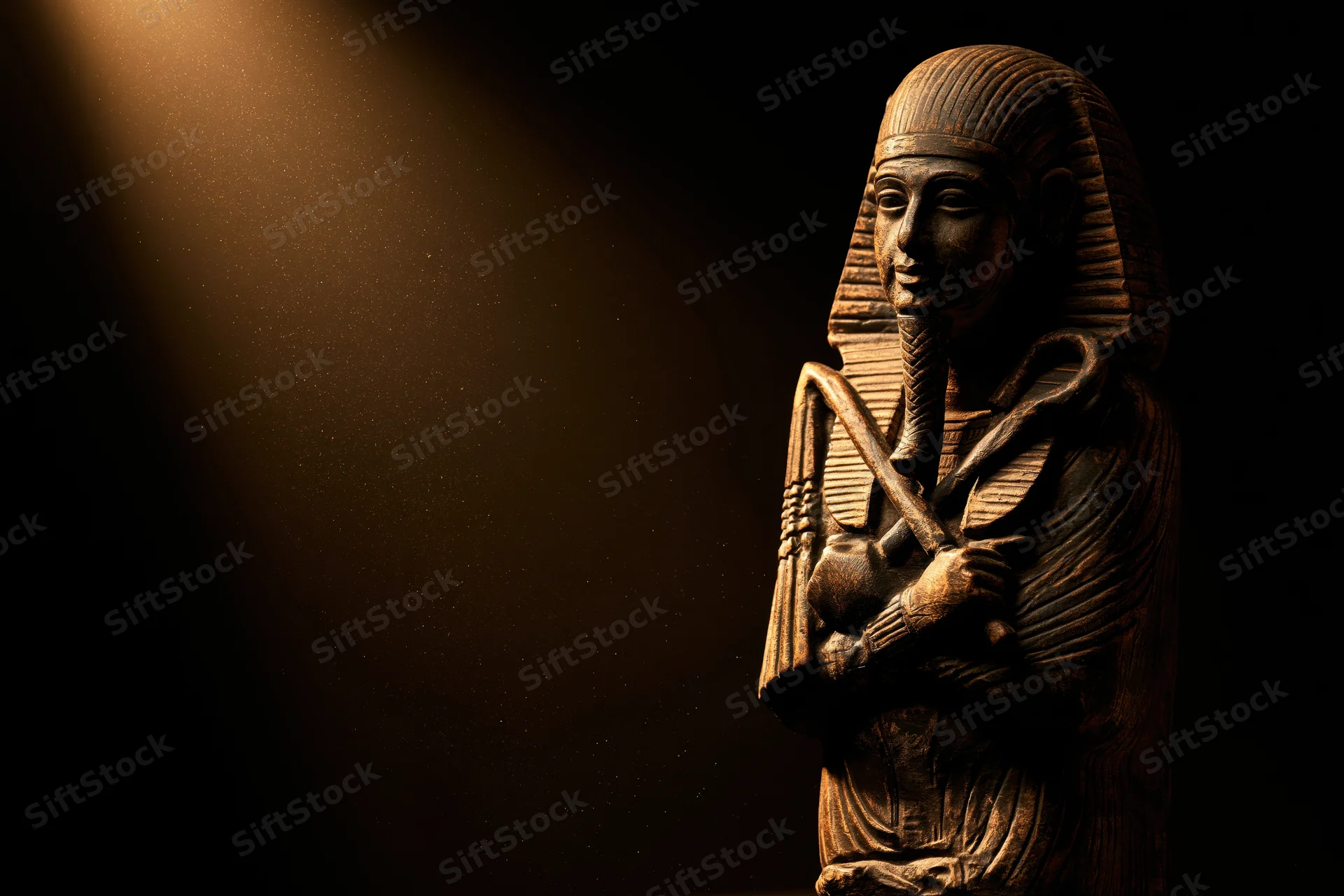 Ancient egyptian pharaoh statue bust carved from stone, illuminated by spotlight against dark background