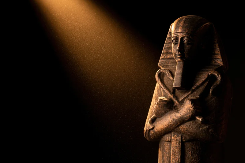Ancient egyptian pharaoh stone statue bust with crossed arms under spotlight in dark setting