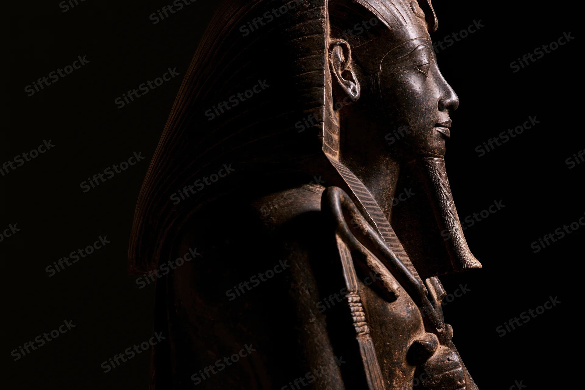 Ancient egyptian pharaoh statue in profile against dark background