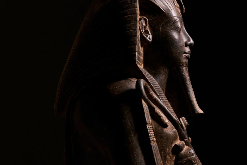 Ancient egyptian pharaoh statue in profile against dark background