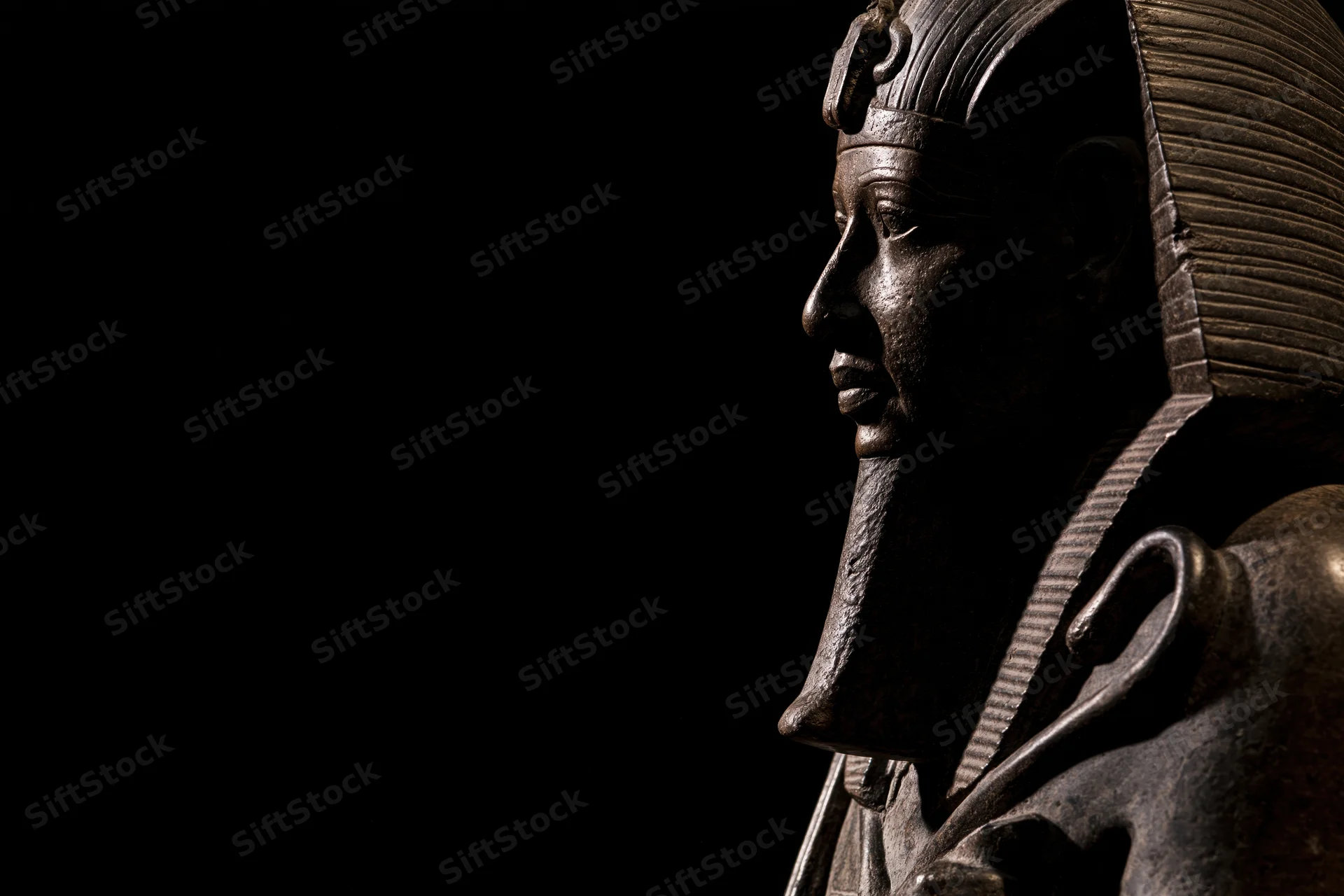 Ancient egyptian pharaoh statue in profile against black background