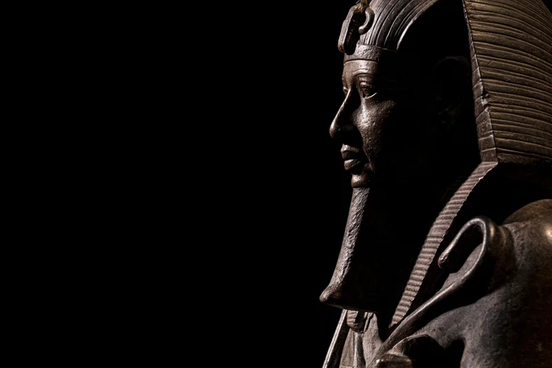 Ancient egyptian pharaoh statue in profile against black background