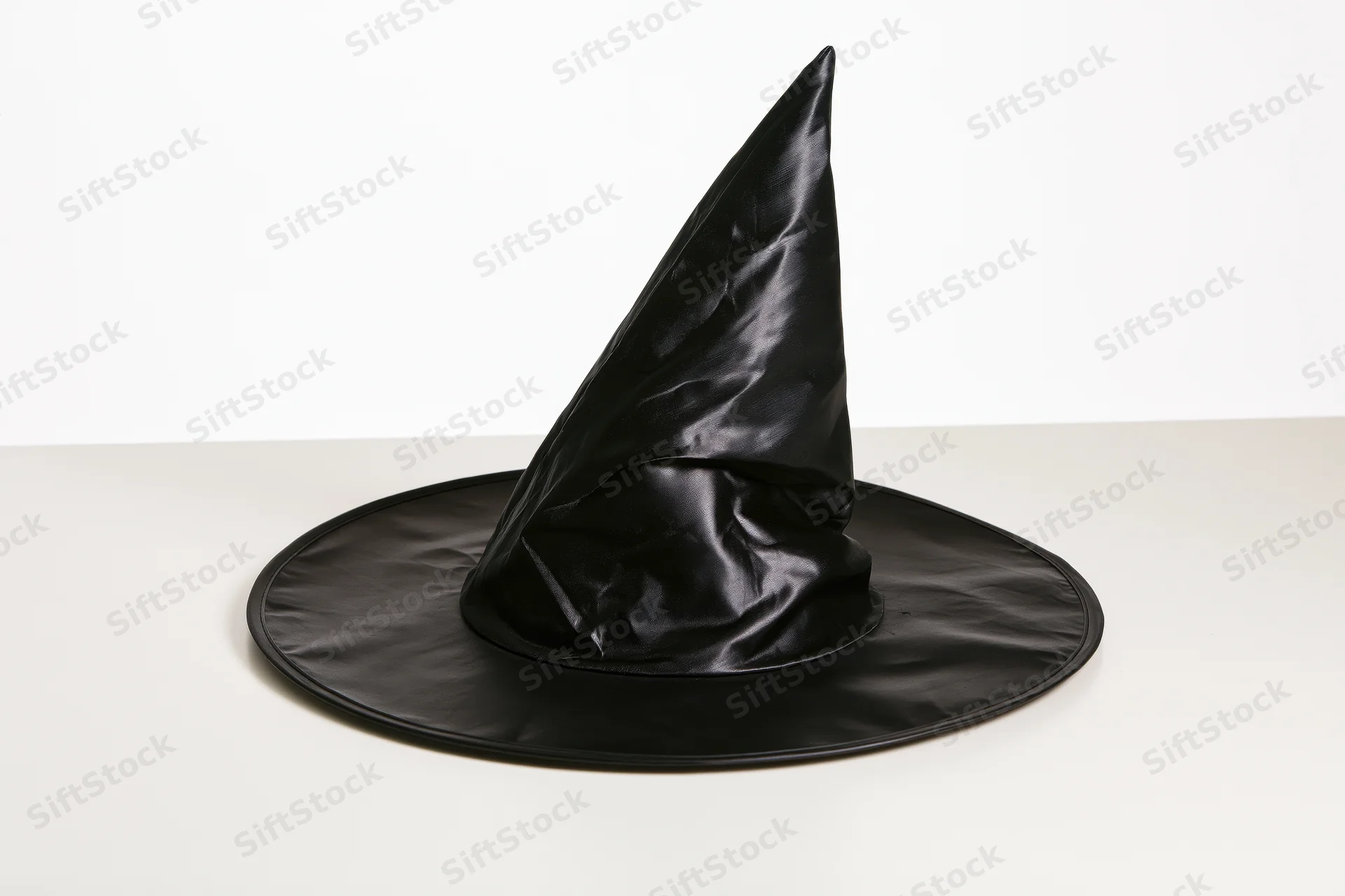 Black plastic witch hat standing upright on a white surface