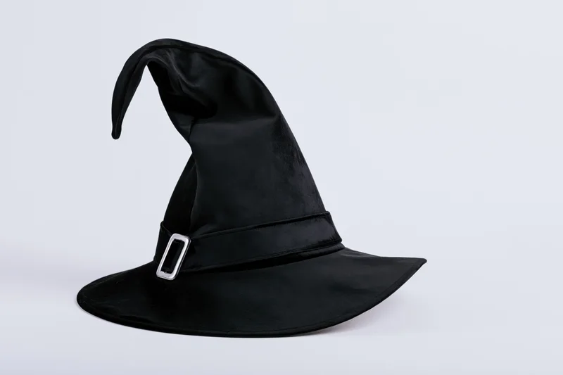 Black witch hat with curved pointed tip and silver buckle on white background