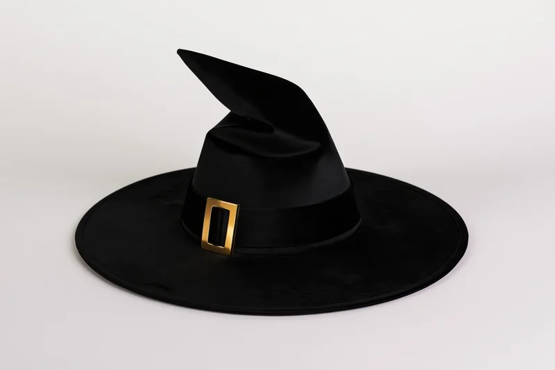 Black witch hat with twisted crown and gold buckle on white background