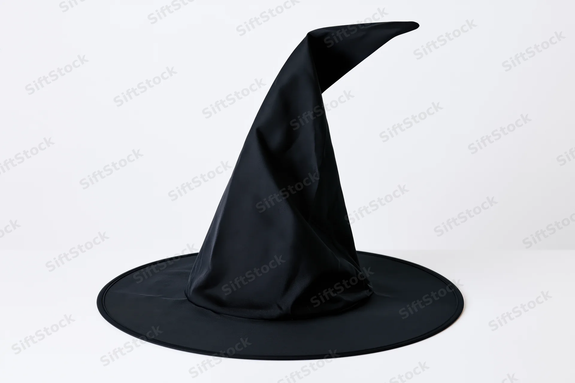 Black witch hat with tall pointed crown and wide flat brim on white surface