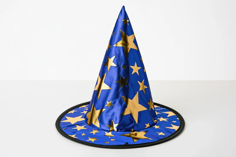 Blue fabric wizard hat with gold foil stars sitting upright on white surface