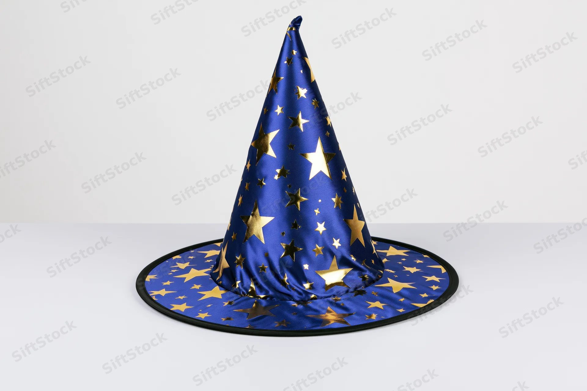Blue wizard hat with gold foil stars standing upright on white surface