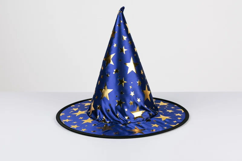 Blue wizard hat with gold foil stars standing upright on white surface