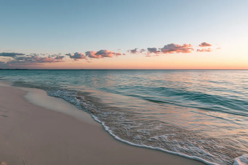 Gentle waves washing over sandy beach at sunset under pastel sky