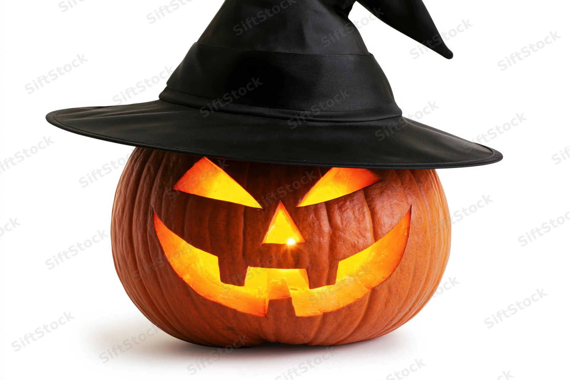 Carved pumpkin with glowing face wearing black witch hat on white background