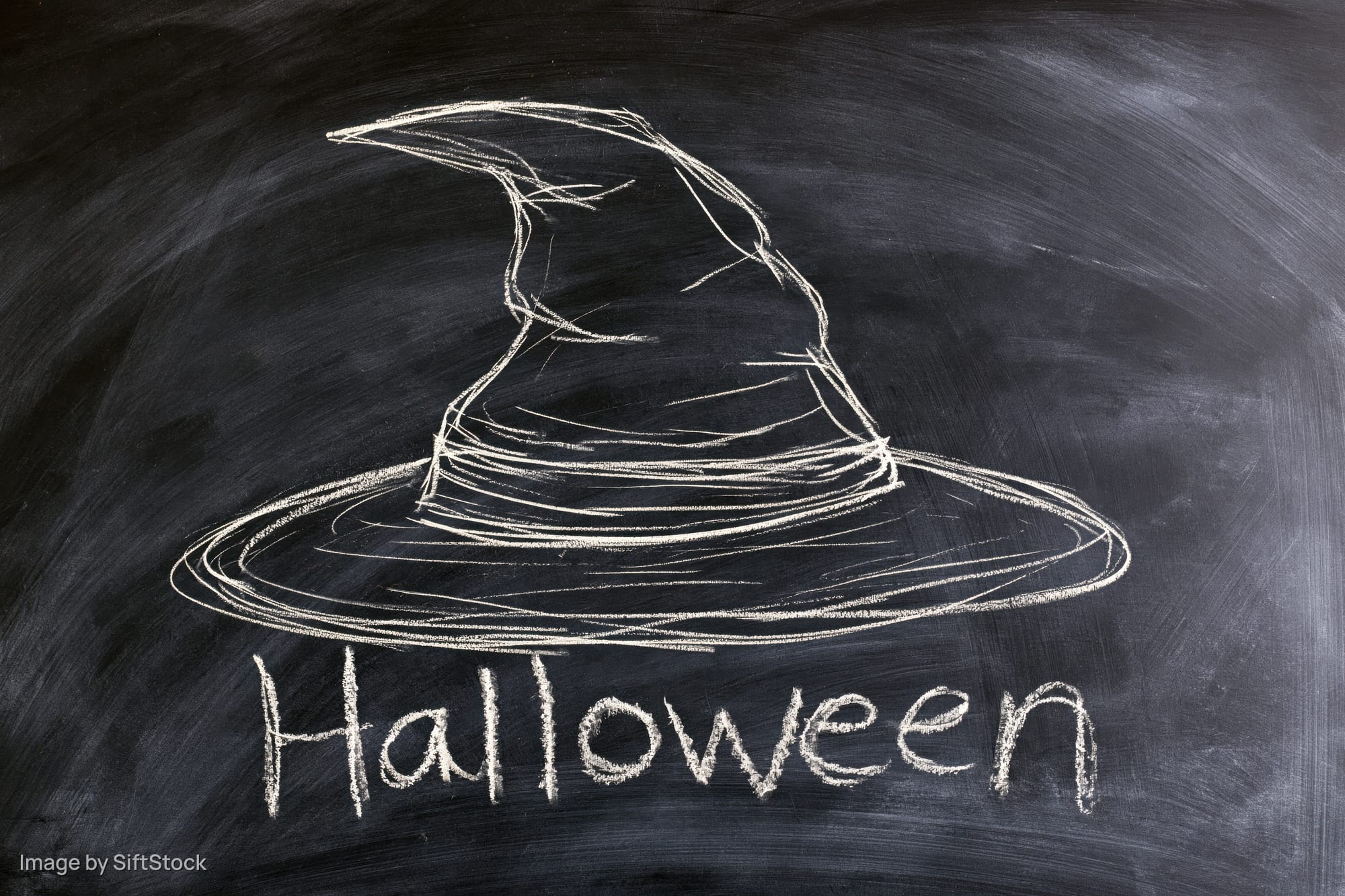 Chalk drawing of a witch hat with the word halloween written on a blackboard