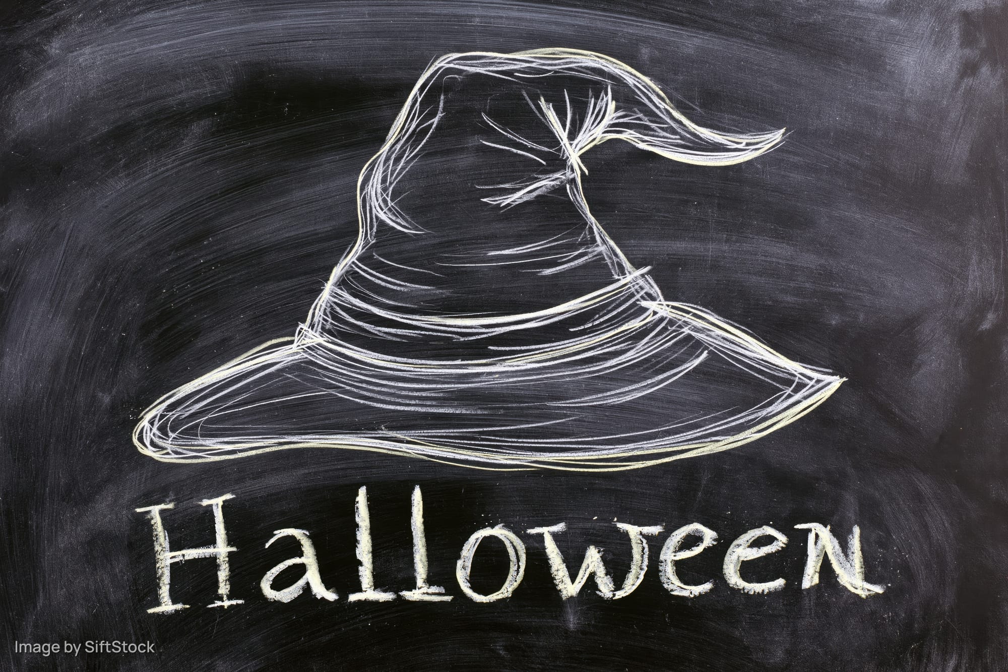 Chalk drawing of a witch hat with the word halloween written below on a blackboard