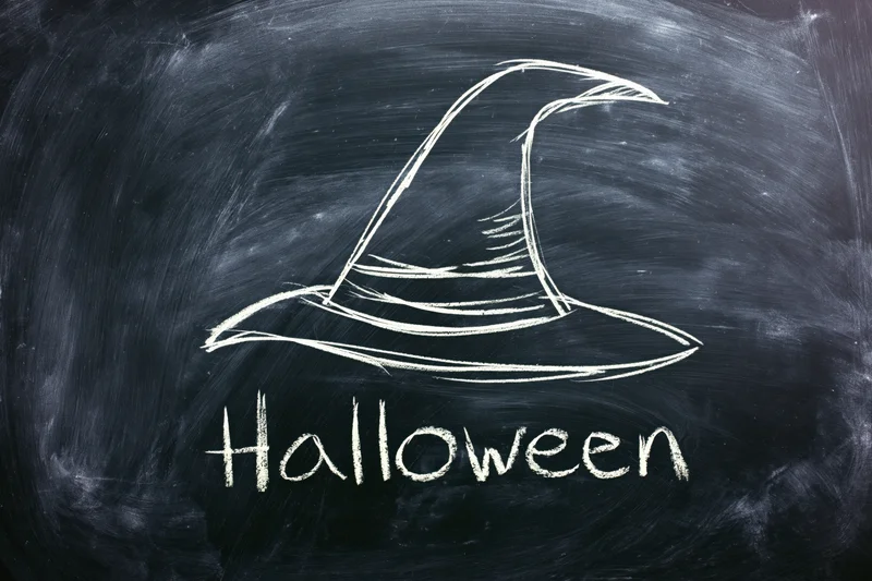 Chalk drawing of a witch hat and the word halloween on a blackboard